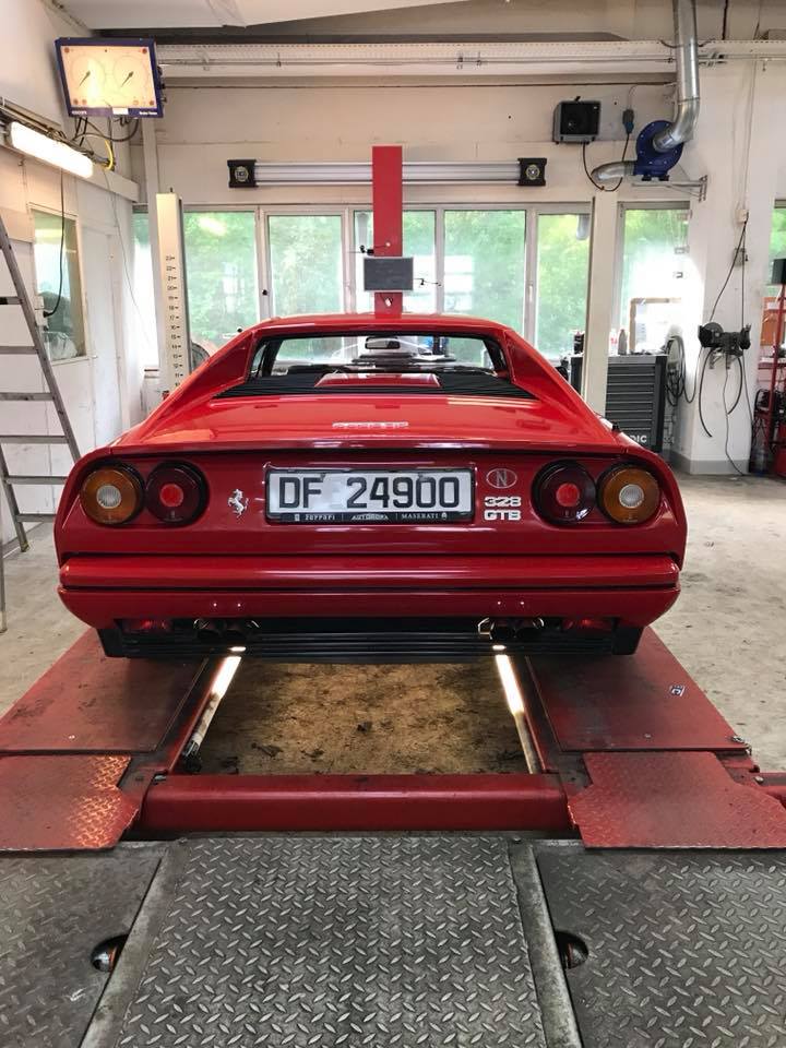 Ferrari Dino 308 GTB bakfra parkert i verksted, klar for vedlikehold eller inspeksjon.